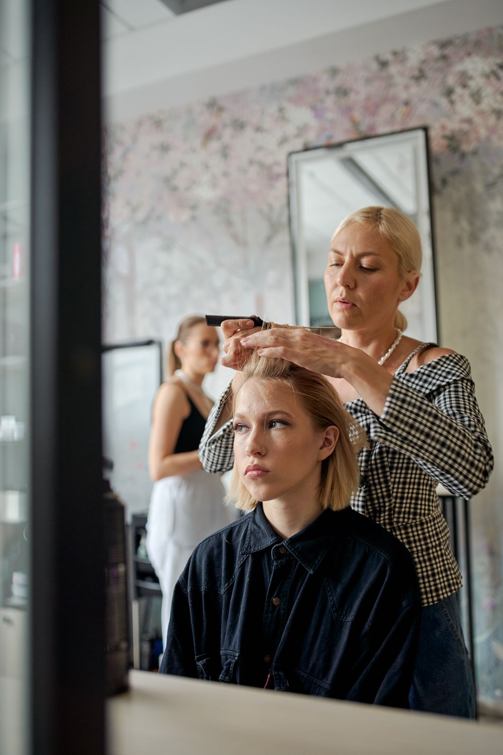 Coiffeuse en train de coiffer une cliente devant un miroir